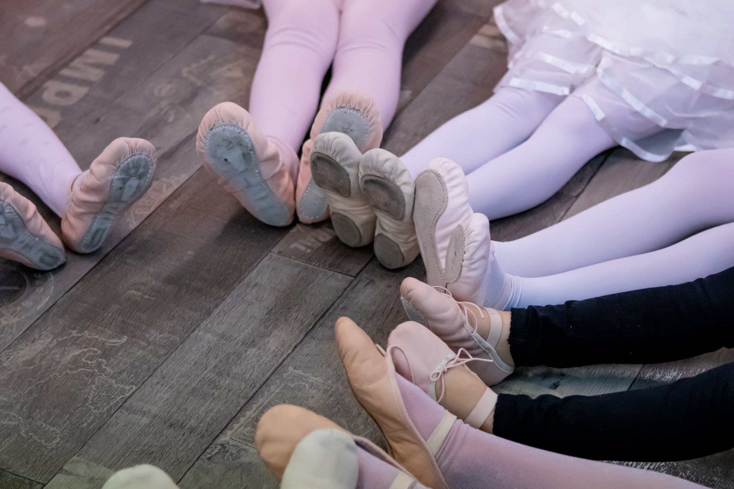 Sapatilhas de ballet de crianças sobre o piso de madeira
