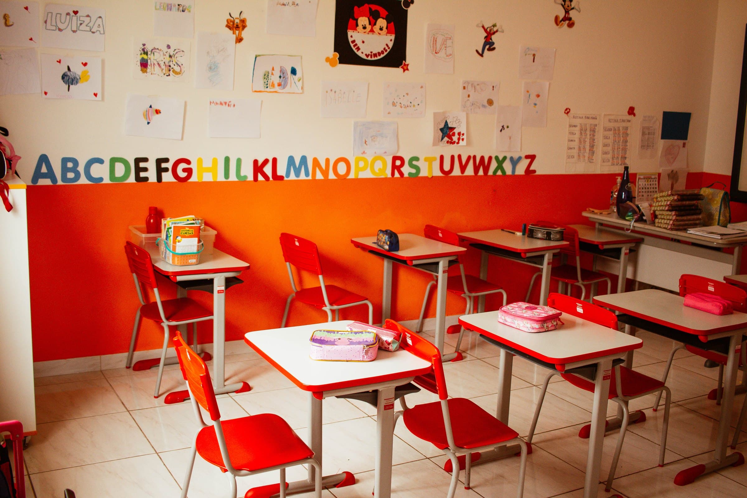 Sala da Educação Infantil do Colégio Jaguaré com o alfabeto na parede e mesas vermelhas
